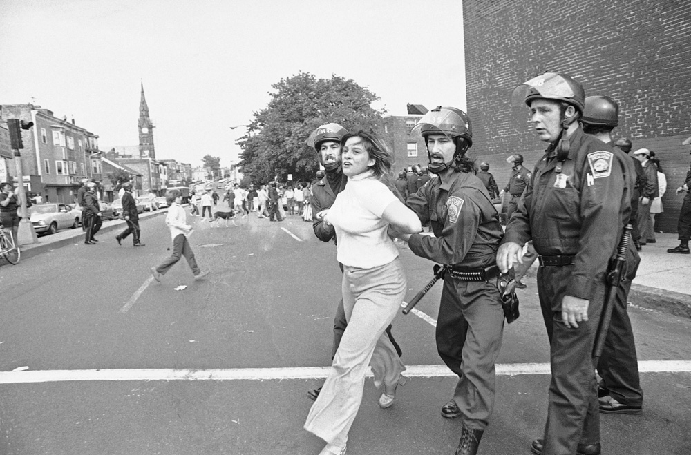 Une jeune femmes est arrêtée par la police anti-émeutes lors des évènements de South Boston de 1974. (Meilleur livre de la semaine : Le silence de Dennis Lehane !).